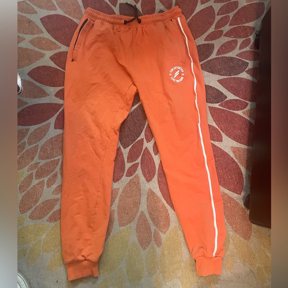 Orange drawstring elastic waste sweat pants with two front zipper pockets